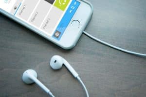 Porzione di uno smartphone con l'app Listen EVERYWHERE con auricolari collegati al telefono