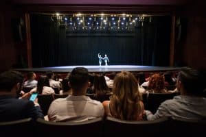 Leute in einem Theater, die eine Generalprobe der darstellenden Künste des Balletts betrachten