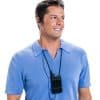 Hombre de mediana edad con cabello oscuro que usa una camisa polo de cuello azul de manga corta, sonriendo mientras usa audífonos y un receptor negro indescriptible que cuelga de un cordón alrededor de su cuello
