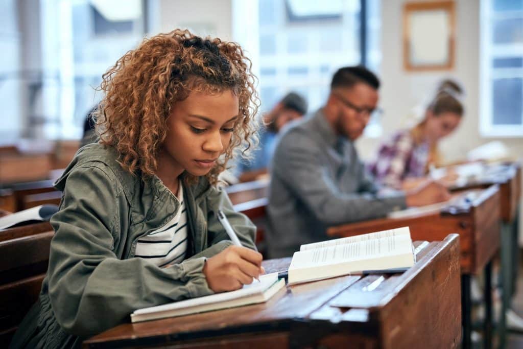 Student, der in einem Klassenzimmer an einem Schreibtisch studiert