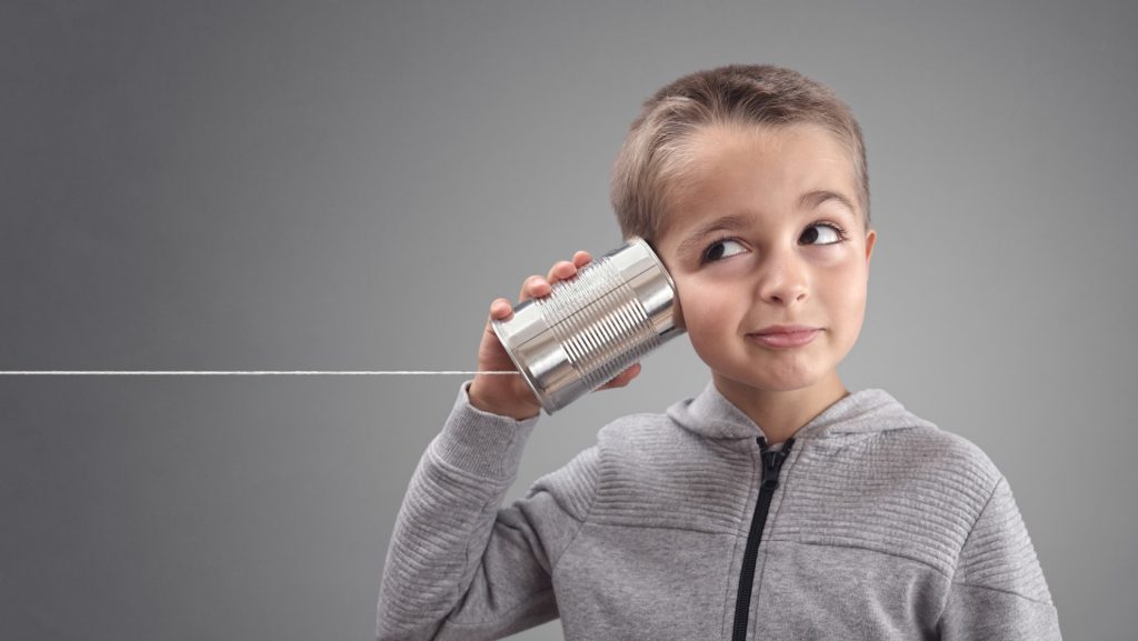 Bambino che ascolta un barattolo di latta con una corda legata