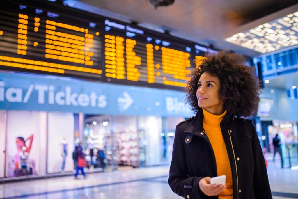 Frauen am Flughafenterminal auf ihrem Handy, die sich die Flugprotokolle ansehen