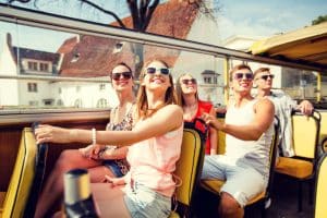 gruppo di amici sorridenti che viaggiano in bus turistico