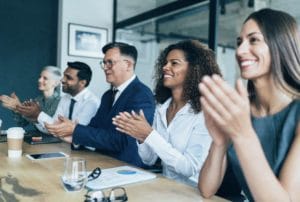 Group of colleagues clapping in a board room.