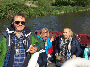 Tre persone con dispositivi di ascolto assistito durante un tour sul fiume