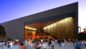 El exterior de Abravanel Hall durante la puesta de sol con mucha gente reunida fuera del edificio.