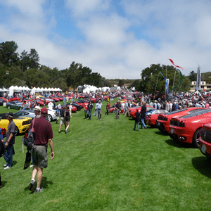 Autoshow mit Autos, die auf dem Gras aufgereiht sind, während Menschenmassen mit einem wunderschönen blauen Himmel und weißen, flauschigen Wolken herumlaufen