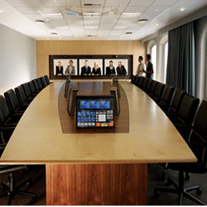 Conference room with 2 people there and 6 people shown meeting virtually through a screen