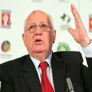 Older gentlemen in suit and tie in front of a branded wall in a conference center