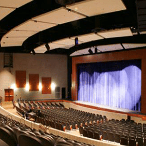 The inside of a theater with a lit up stage and no one sitting in the seats