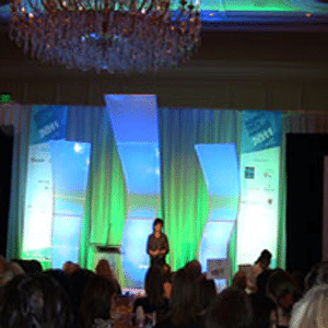 A woman on a brightly lit stage at the women in tech council