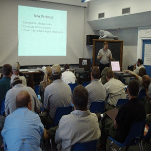 Group of attendees looking up at a slideshow presentation next to a presenter