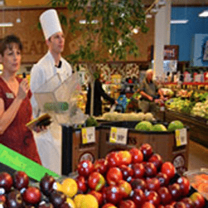 Deux chefs culinaires debout devant un étalage de produits.