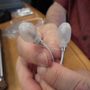 Someone holding new ear buds that protect your ears with balloons