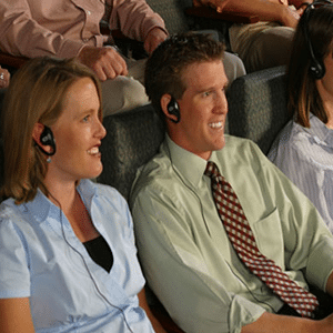 Hombre y mujer sonriendo escuchando a través de un sistema de asistencia auditiva