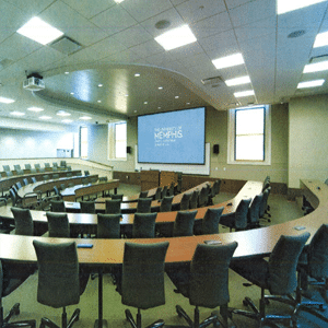 Aerial view of an empty college classroom with empty tables and chairs with a large projector display