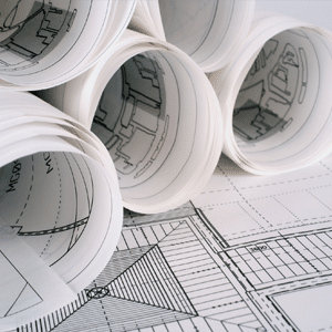 Plans de spécification de bâtiment enroulés sur un bureau.