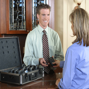 Smiling employee handing a woman an assistive listening device