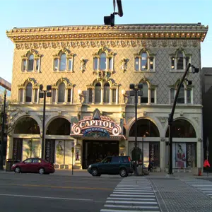 Vista de la calle del frente del Utah Capitol Theatre, un ornamentado edificio de tres pisos de color blanquecino con un gran cartel del Capitol Theatre sobre la puerta