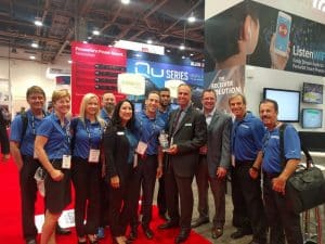 Groupe d'employés en 2016 devant le stand à infocomm