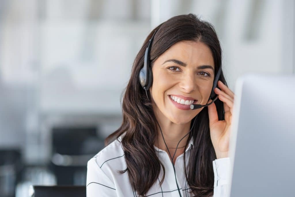 Glückliche lächelnde Frau, die im Callcenter arbeitet