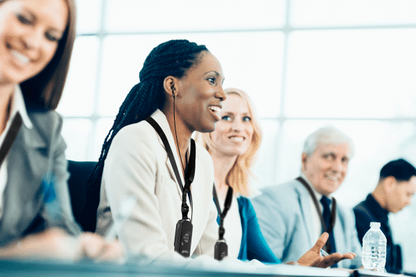 Gruppo di persone a una conferenza di lavoro con i ricevitori di ascolto mentre partecipano a una conversazione di gruppo