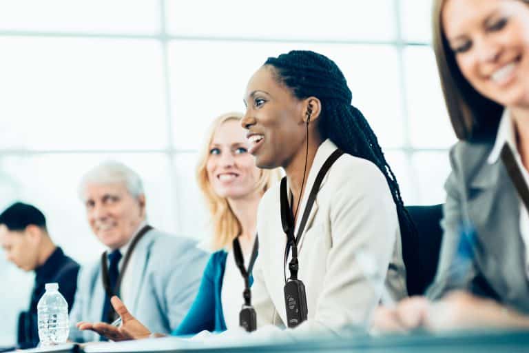 Business woman listening to conference audio through assistive listening device