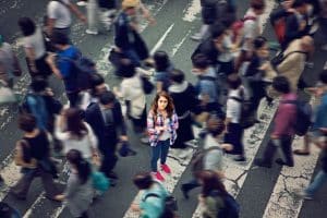 Junge Frau, die sich in einer geschäftigen Menschenmenge in der Stadt isoliert fühlt