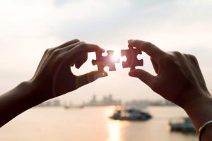 Two hands holding puzzle pieces