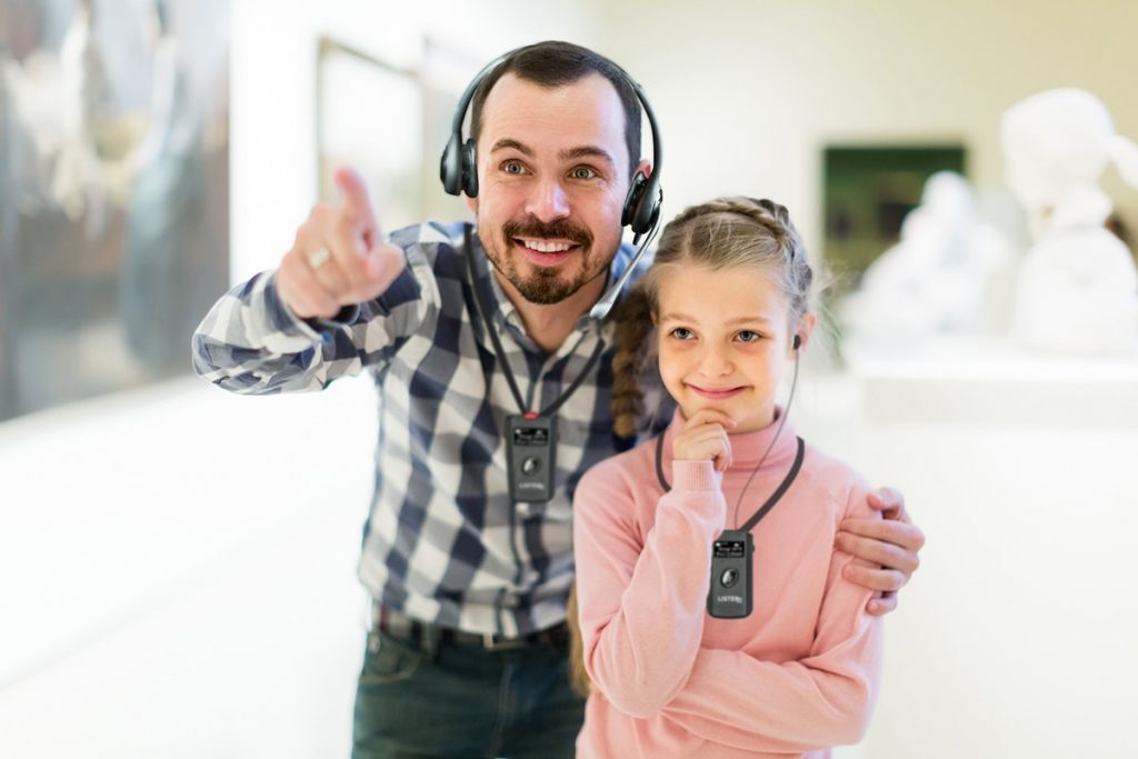 Vater und Tochter gehen mit Hörhilfen durch die Galerie