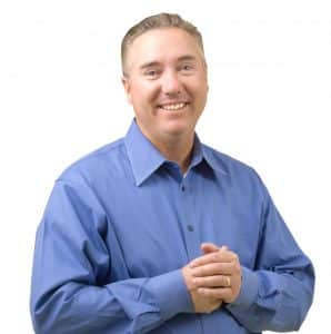 headshot image of our Founder, Russ Gentner with him smiling while pressing his hands together