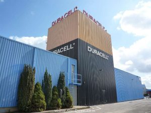 Gran edificio de metal azul con el centro del edificio más alto y pintado para parecerse a una batería Duracell