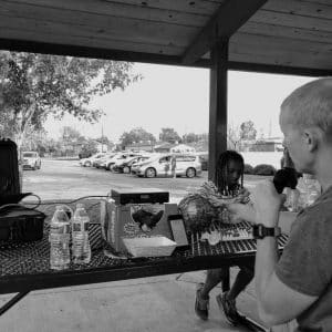 Personas que juegan un juego de bingo al aire libre bajo un pabellón.
