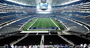 Amplia vista de un estadio vacío de los Dallas Cowboys con algunos jugadores en el campo