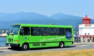 Bus turístico junto al mar con asistentes adentro.