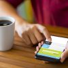 Hand holding a smart phone on a wooden desk. The smart phone is an Samsung Galaxy S9 plus. Samsung Galaxy is a touchscreen smart phone produced by Samsung Electronics.