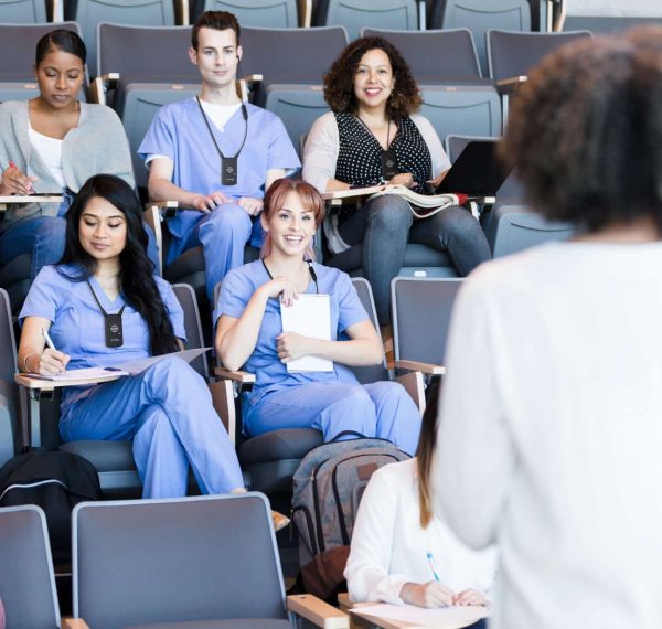 A class of attentive medical students listen to a mature female professor's lecture.