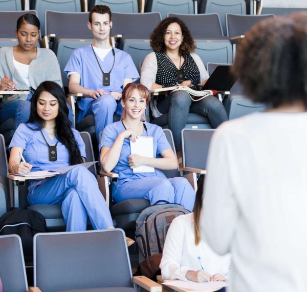 Professor teaches a class of medical students A class of attentive medical students listen to a mature female professor's lecture.